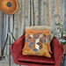A cubic printed cushion on faux linen in shades of orange with a gold foil