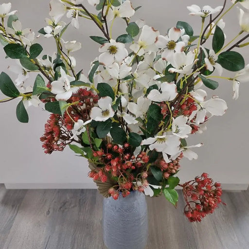 A realistic faux decorative stem of green leaves and red berries