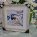 A marbled print of blues, creams and gold in an antique white frame