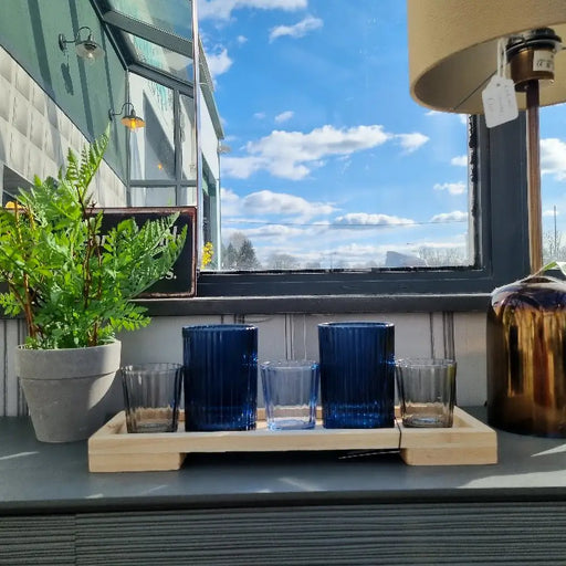 A collection of 5 navy and black glass tealight holders with a wooden tray