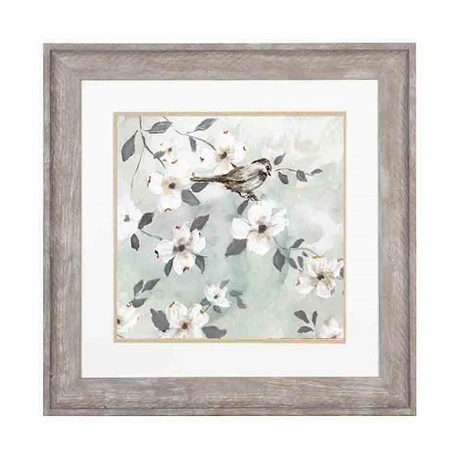A resting bird among flower covered branches print in an antique white frame