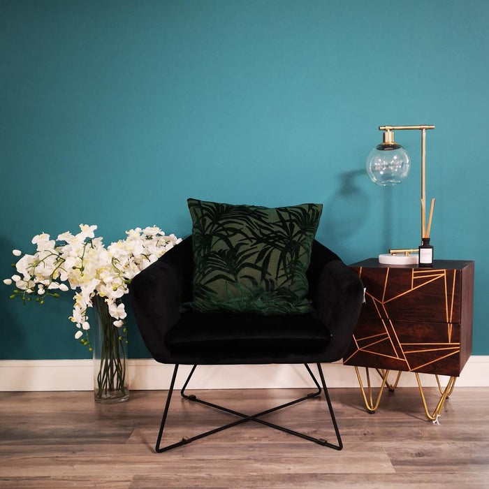 A living room setting with a black occasional seat and a SOUTH ROW Globe brass-effect table lamp featuring a glass globe, metal stem and marble base