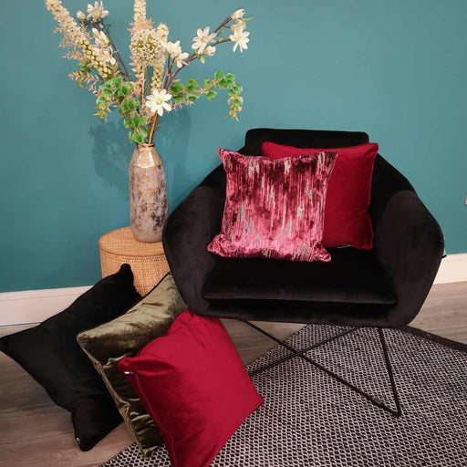 A living room setting with a black occasional seat and Scatter Box Nova Berry lavish cut velvet cushion in a contemporary style with a coordinating velvet reverse