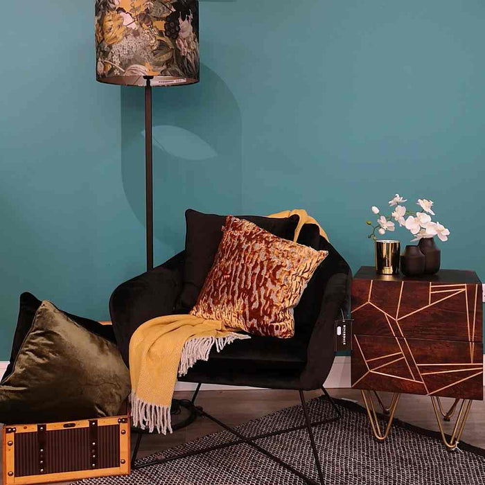 A living room setting with a black occasional seat and Scatter Box Tigris antique gold lavish cut velvet cushion in a contemporary style with a linen content reverse