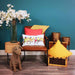 A living room setting with a brown leather chair and Sunita cushion featuring a dawn chorus of colourful birds