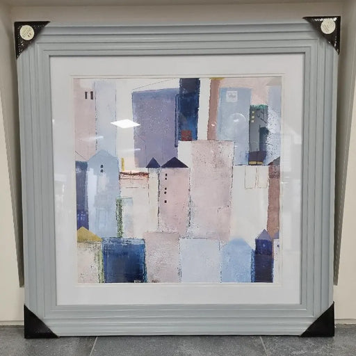 An abstract village setting print in blues & yellows with a grey frame
