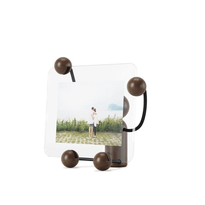 Woody picture frame held up by a cute, black/walnut wooden figure